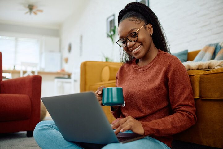 Woman attending an online event at her laptop with a cup of tea
